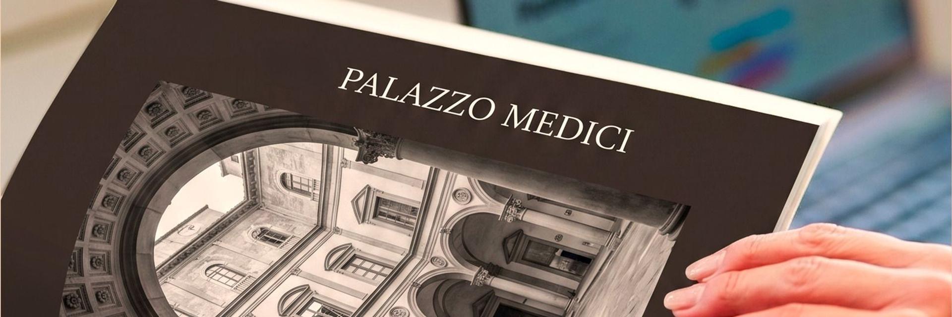 Un libro d'arte sul Palazzo Medici sfogliato accanto a un portatile: lo studio della borsa Milva Tinarel